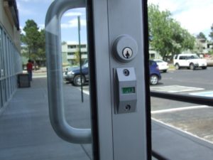 Storefront door with an indicator lock showing open or locked status, commonly rekeyed for commercial access control.