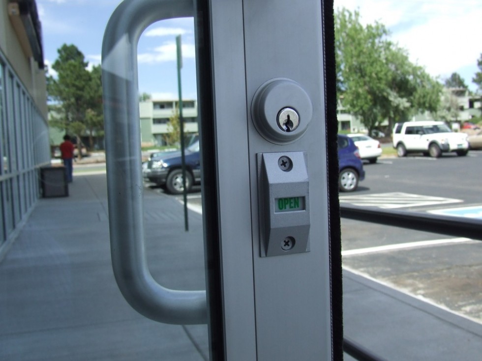 Storefront door with an indicator lock showing open or locked status, commonly rekeyed for commercial access control.