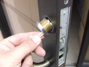 Mortise cylinder being rekeyed or replaced on a commercial glass storefront door in Denver.