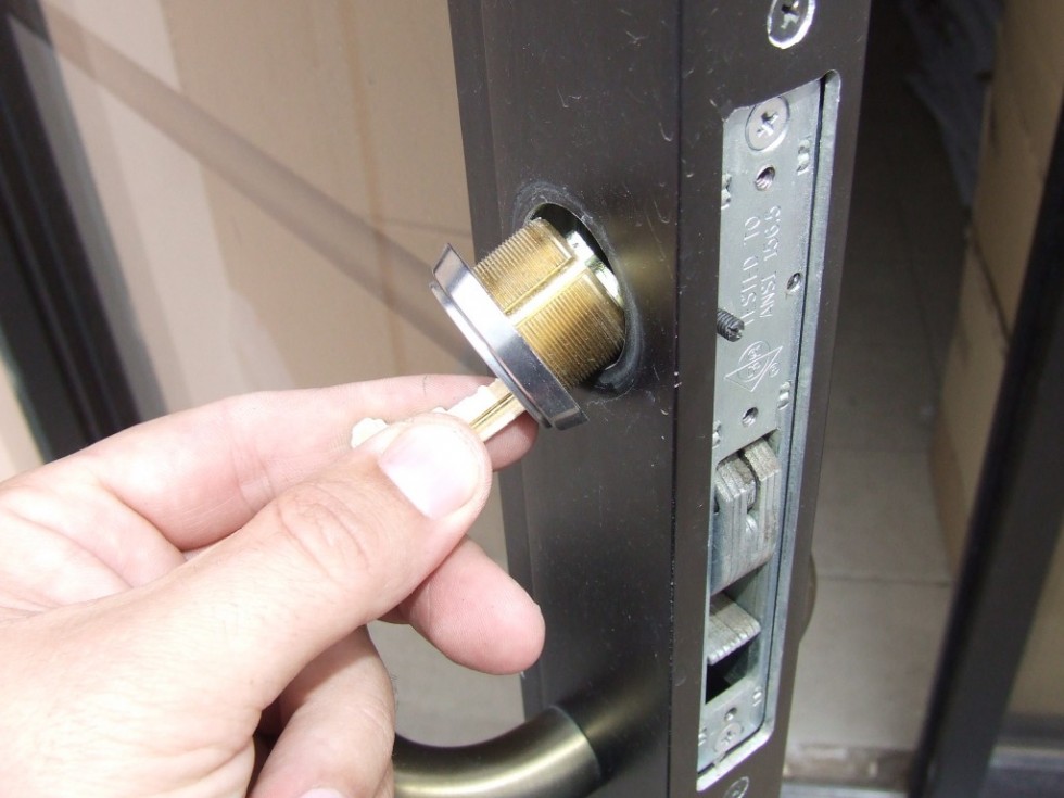 Mortise cylinder being rekeyed or replaced on a commercial glass storefront door in Denver.