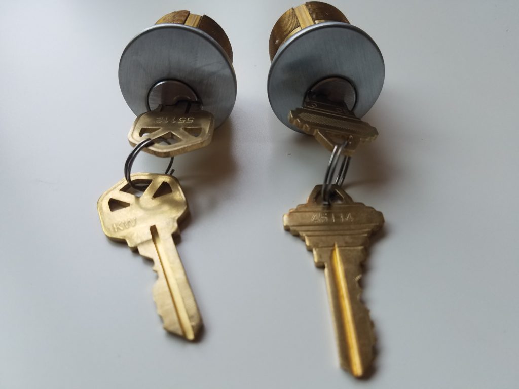 Two mortise cylinder locks keyed differently—one with a Kwikset key and one with a Schlage key.
